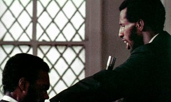Movie still from “Ganja & Hess” (1973), directed by Bill Gunn – A man is holding a microphone in his hand; Close Up shot, Over the shoulder angle