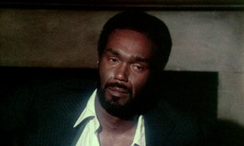Movie still from “Ganja & Hess” (1973), directed by Bill Gunn – A man with a beard and a white shirt; Close Up shot, High angle