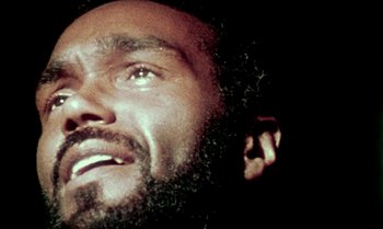 Movie still from “Ganja & Hess” (1973), directed by Bill Gunn – A person with a beard looking up; Extreme Close Up shot, Overhead angle