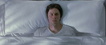 Movie still from “Garden State” (2004), directed by Zach Braff – A man laying in a bed under a white blanket; Medium shot, Overhead angle