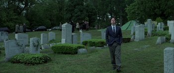 Movie still from “Garden State” (2004), directed by Zach Braff – A man in a suit standing in front of a grave yard; Wide shot, Low angle