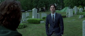Movie still from “Garden State” (2004), directed by Zach Braff – A man in a suit standing in front of a cemetery; Medium shot, Low angle
