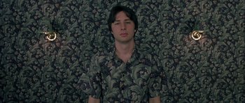 Movie still from “Garden State” (2004), directed by Zach Braff – A man in a floral shirt standing in front of a wall; Medium shot, Overhead angle