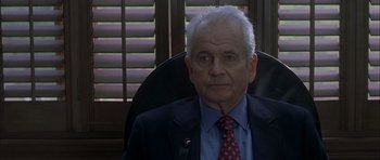 Movie still from “Garden State” (2004), directed by Zach Braff – An older man wearing a suit and tie sitting in an office chair; Close Up shot, Over the shoulder angle