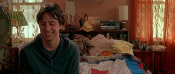Movie still from “Garden State” (2004), directed by Zach Braff – A man sitting on top of a bed in a room; Medium shot, Over the shoulder angle