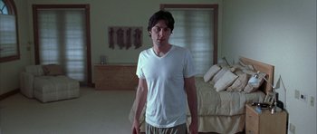 Movie still from “Garden State” (2004), directed by Zach Braff – A man standing in a room with a bed in the background; Medium shot, Low angle