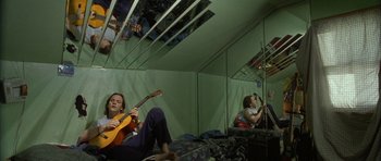 Movie still from “Garden State” (2004), directed by Zach Braff – A man sitting on a bed playing a guitar; Wide shot, Overhead angle