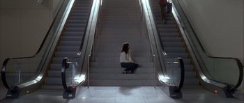 Movie still from “Garden State” (2004), directed by Zach Braff – A woman sitting on the bottom step of an escalator; Wide shot, High angle