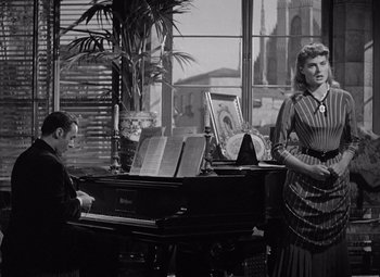 Movie still from “Gaslight” (1944), directed by George Cukor – A man and a woman are playing piano in a living room; Medium shot, Low angle
