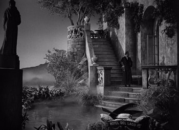 Movie still from “Gaslight” (1944), directed by George Cukor – A black and white photo of a man standing on stairs; Extreme Wide shot, High angle