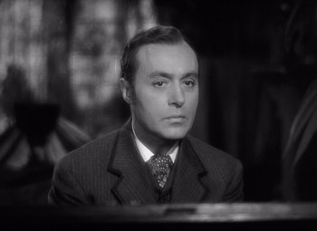 Movie still from “Gaslight” (1944), directed by George Cukor – A man wearing a suit and tie sitting in front of a table; Close Up shot, High angle
