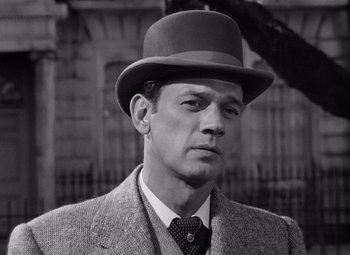 Movie still from “Gaslight” (1944), directed by George Cukor – A black and white photo of a man wearing a suit and a hat; Close Up shot, Over the shoulder angle