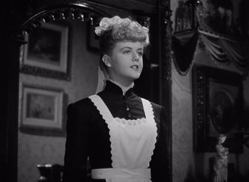 Movie still from “Gaslight” (1944), directed by George Cukor – A woman in an old fashioned dress standing in front of a mirror; Medium shot, Low angle