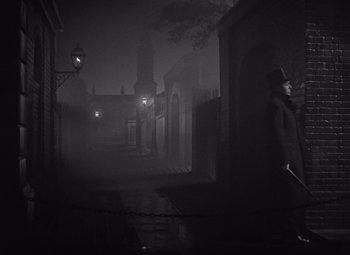 Movie still from “Gaslight” (1944), directed by George Cukor – A man walking down a street in a dark city; Wide shot, High angle