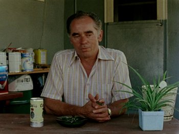 Movie still from “Gates of Heaven” (1978), directed by Errol Morris – An older man sitting at a table with a bowl of food; Medium shot, High angle