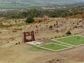 Movie still from “Gates of Heaven” (1978), directed by Errol Morris – An aerial view of an american flag flying over a field; Extreme Wide shot, High angle