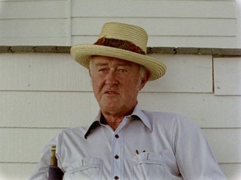 Movie still from “Gates of Heaven” (1978), directed by Errol Morris – An older man wearing a straw hat and holding a wine bottle; Close Up shot, Low angle