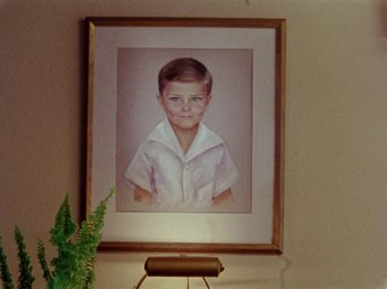 Movie still from “Gates of Heaven” (1978), directed by Errol Morris – A portrait of a young boy hanging on the wall; Extreme Close Up shot, Low angle