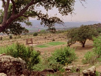 Movie still from “Gates of Heaven” (1978), directed by Errol Morris – An aerial view of an open field in the middle of the desert; Extreme Wide shot, High angle