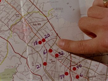 Movie still from “Gates of Heaven” (1978), directed by Errol Morris – A hand pointing to a map with red dots on it; Extreme Close Up shot, Overhead angle