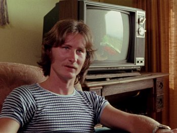 Movie still from “Gates of Heaven” (1978), directed by Errol Morris – A man sitting in front of a television in a living room; Close Up shot, High angle