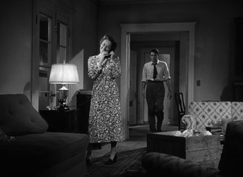 Movie still from “Gentleman's Agreement” (1947), directed by Elia Kazan – An old photo of a woman and a man standing in a living room; Wide shot, Low angle