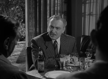 Movie still from “Gentleman's Agreement” (1947), directed by Elia Kazan – A man sitting at a table with a bottle of beer; Medium shot, Over the shoulder angle