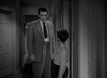 Movie still from “Gentleman's Agreement” (1947), directed by Elia Kazan – A man in a suit and tie standing next to a boy in a hallway; Medium shot, Over the shoulder angle