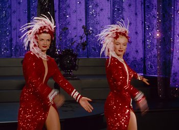 Movie still from “Gentlemen Prefer Blondes” (1953), directed by Howard Hawks – A couple of women in red dresses dancing on a stage; Medium shot, Low angle