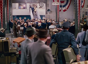 Movie still from “Gentlemen Prefer Blondes” (1953), directed by Howard Hawks – A group of men standing in a room with suitcases; Extreme Wide shot, High angle