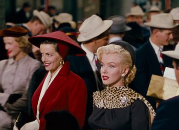 Movie still from “Gentlemen Prefer Blondes” (1953), directed by Howard Hawks – A group of people standing next to each other wearing hats; Medium shot, Over the shoulder angle
