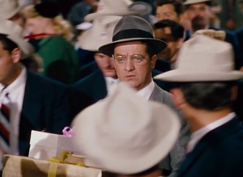 Movie still from “Gentlemen Prefer Blondes” (1953), directed by Howard Hawks – A man wearing a hat and glasses; Medium shot, Over the shoulder angle