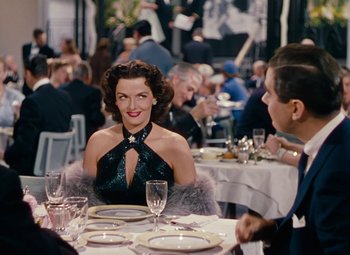 Movie still from “Gentlemen Prefer Blondes” (1953), directed by Howard Hawks – A woman sitting at a dinner table with a man; Medium shot, Over the shoulder angle