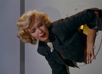 Movie still from “Gentlemen Prefer Blondes” (1953), directed by Howard Hawks – A woman in a black jacket is leaning against a wall; Medium shot, Low angle