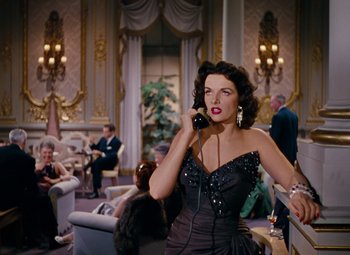 Movie still from “Gentlemen Prefer Blondes” (1953), directed by Howard Hawks – A woman talking on a phone while wearing a black dress; Medium shot, Low angle