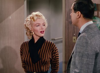 Movie still from “Gentlemen Prefer Blondes” (1953), directed by Howard Hawks – A woman in a checkered dress and a man in a suit; Medium shot, Over the shoulder angle