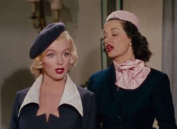 Movie still from “Gentlemen Prefer Blondes” (1953), directed by Howard Hawks – Two beautiful women in hats and jackets standing next to each other; Medium shot, Low angle