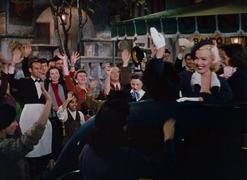 Movie still from “Gentlemen Prefer Blondes” (1953), directed by Howard Hawks – A group of people standing in front of a microphone; Wide shot, High angle