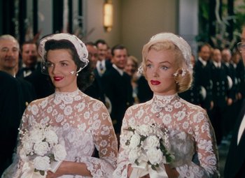 Movie still from “Gentlemen Prefer Blondes” (1953), directed by Howard Hawks – Two women dressed in wedding attire and holding flowers; Medium shot, Over the shoulder angle