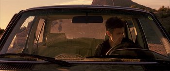 Movie still from “Gerry” (2002), directed by Gus Van Sant – A man driving a car in the sun; Close Up shot, Low angle