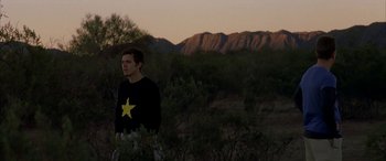 Movie still from “Gerry” (2002), directed by Gus Van Sant – A man standing in the middle of a field with mountains in the background; Medium shot, Over the shoulder angle