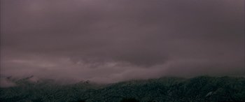 Movie still from “Gerry” (2002), directed by Gus Van Sant – A dark cloudy sky over a mountainous area; Extreme Wide shot, Low angle