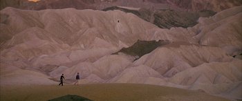 Movie still from “Gerry” (2002), directed by Gus Van Sant – A man is standing on the side of a mountain; Extreme Wide shot, High angle