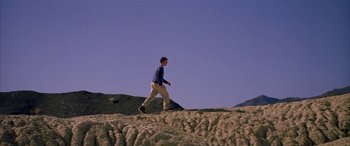 Movie still from “Gerry” (2002), directed by Gus Van Sant – A man is walking on the sand dunes; Extreme Wide shot, Low angle
