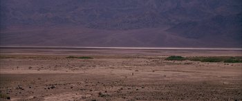 Movie still from “Gerry” (2002), directed by Gus Van Sant – A person standing in the middle of an empty desert; Extreme Wide shot, High angle