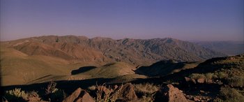 Movie still from “Gerry” (2002), directed by Gus Van Sant – A view of a mountain range from the top of a hill; Extreme Wide shot, High angle