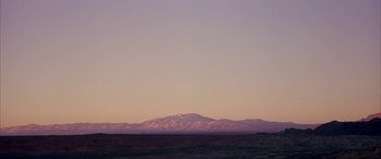 Movie still from “Gerry” (2002), directed by Gus Van Sant – A view of a mountain range with a sky in the background; Extreme Wide shot, Low angle