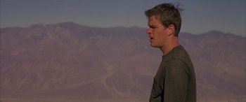Movie still from “Gerry” (2002), directed by Gus Van Sant – A man standing in front of a mountain range looking off into the distance; Close Up shot, Low angle