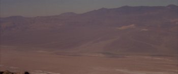 Movie still from “Gerry” (2002), directed by Gus Van Sant – A view of a desert landscape with mountains in the background; Extreme Wide shot, Low angle