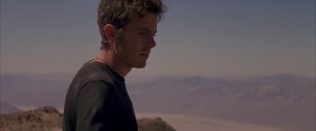 Movie still from “Gerry” (2002), directed by Gus Van Sant – A young man standing on top of a hill; Close Up shot, Low angle